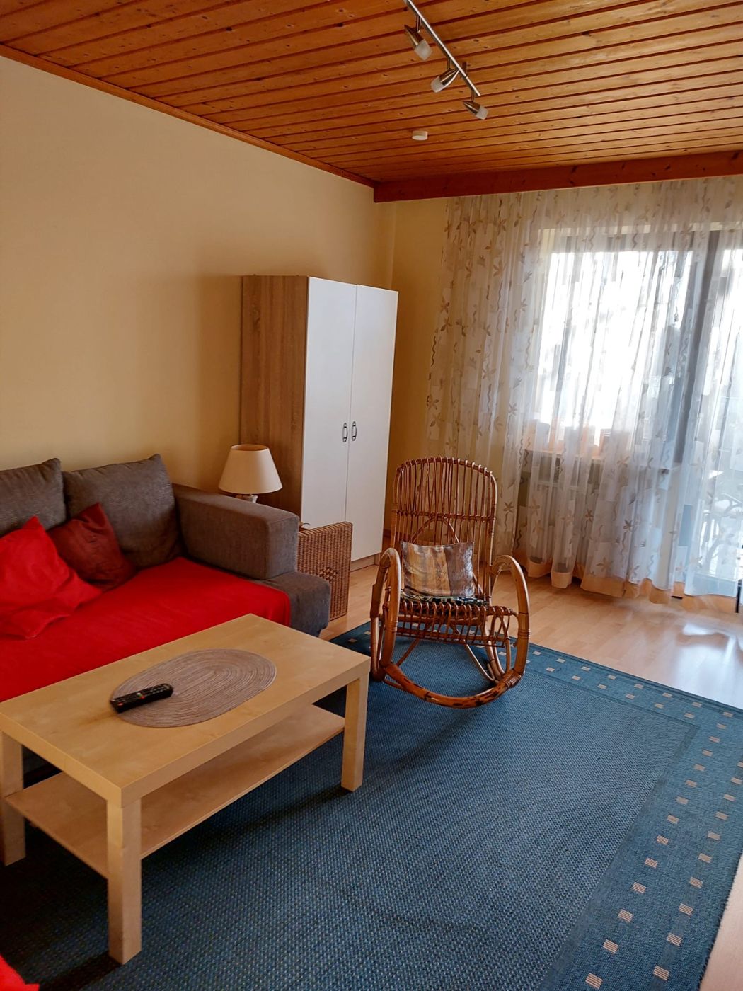 Wohnzimmer mit Holzdecke, Sofa und Schaukelstuhl